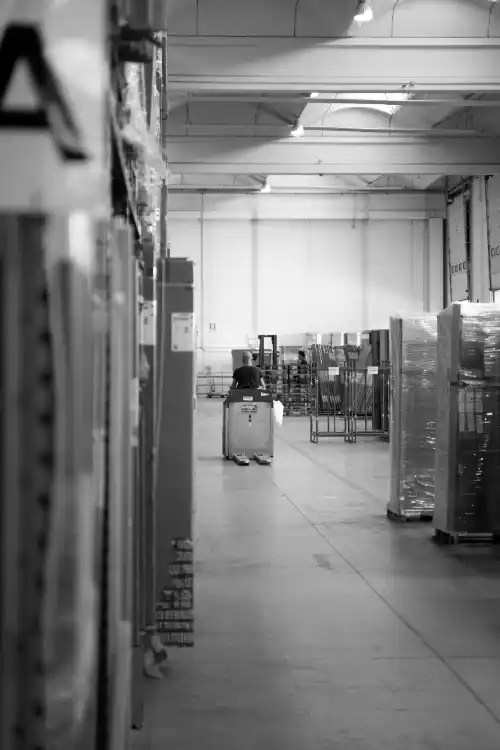 Operaio guida muletto AGV (bene soggetto a iperammortamento) in magazzino, tra la merce 