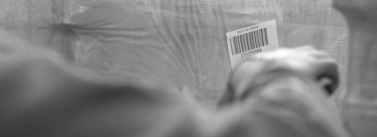 Operatore di magazzino scansiona il codice a barre dell'unit&agrave; di carico (pallet) con software WMS da terminale mobile